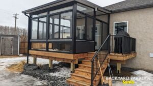 Black studio sunroom with treated wood deck and black aluminum railings, Stonewall, Manitoba 1