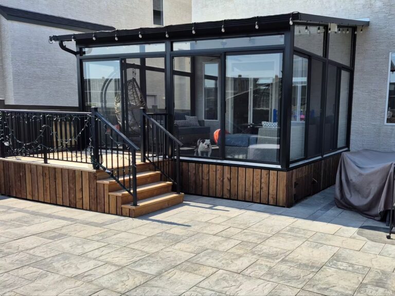 Black studio sunroom with treated wood deck and black aluminum railings in South St Vital, Winnipeg