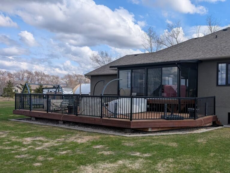 Black studio sunroom with treated wood deck and black aluminum railings built in Linden, Manitoba