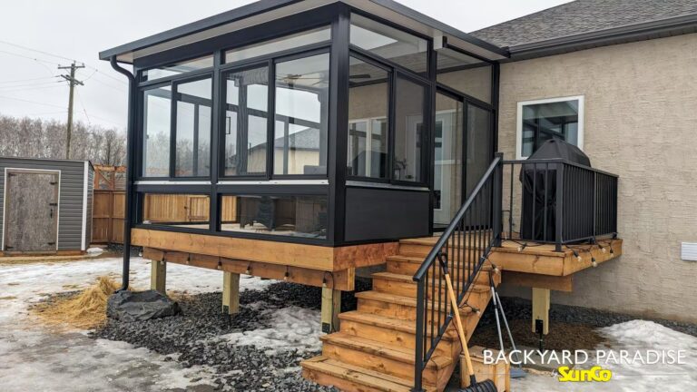 Black elevated studio sunroom with treated wood deck and black aluminum railings in Stonewall, Manitoba